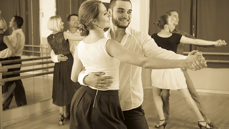 Tangoelever i sal med spejle monochrom bruntonet