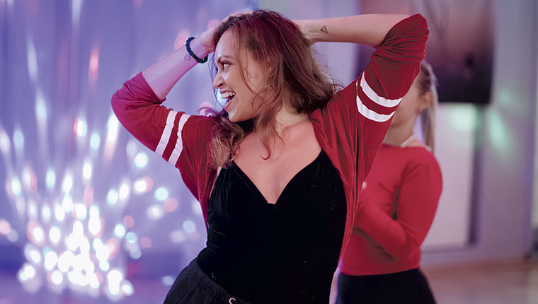 Happy young woman in black and read dancing